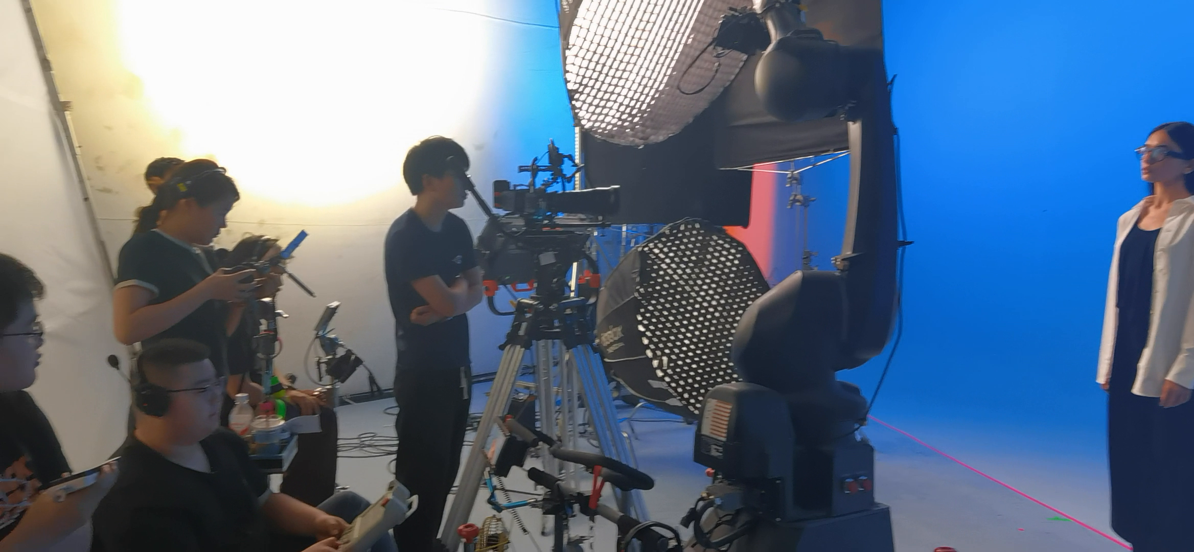 Production crew operating a robotic camera on a blue studio set