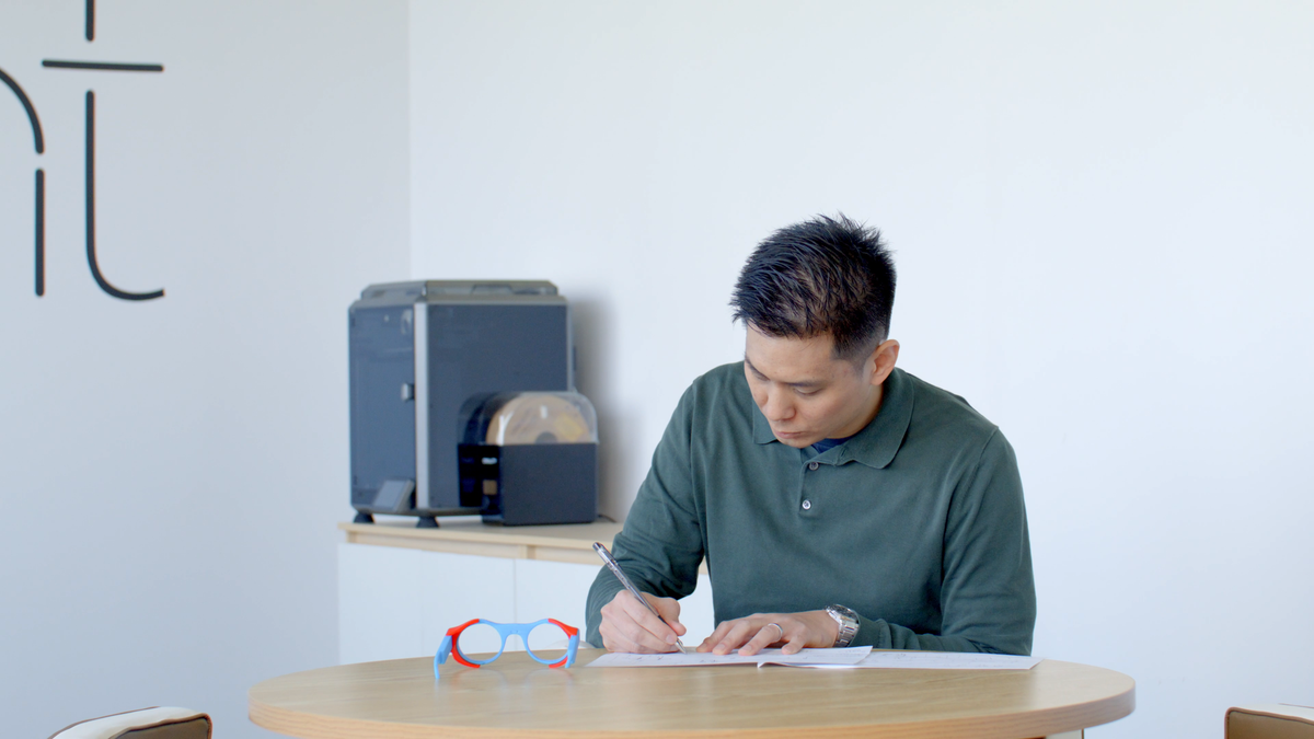 8ight engineer sketching beside colored camera-glasses prototypes during an early product study.
