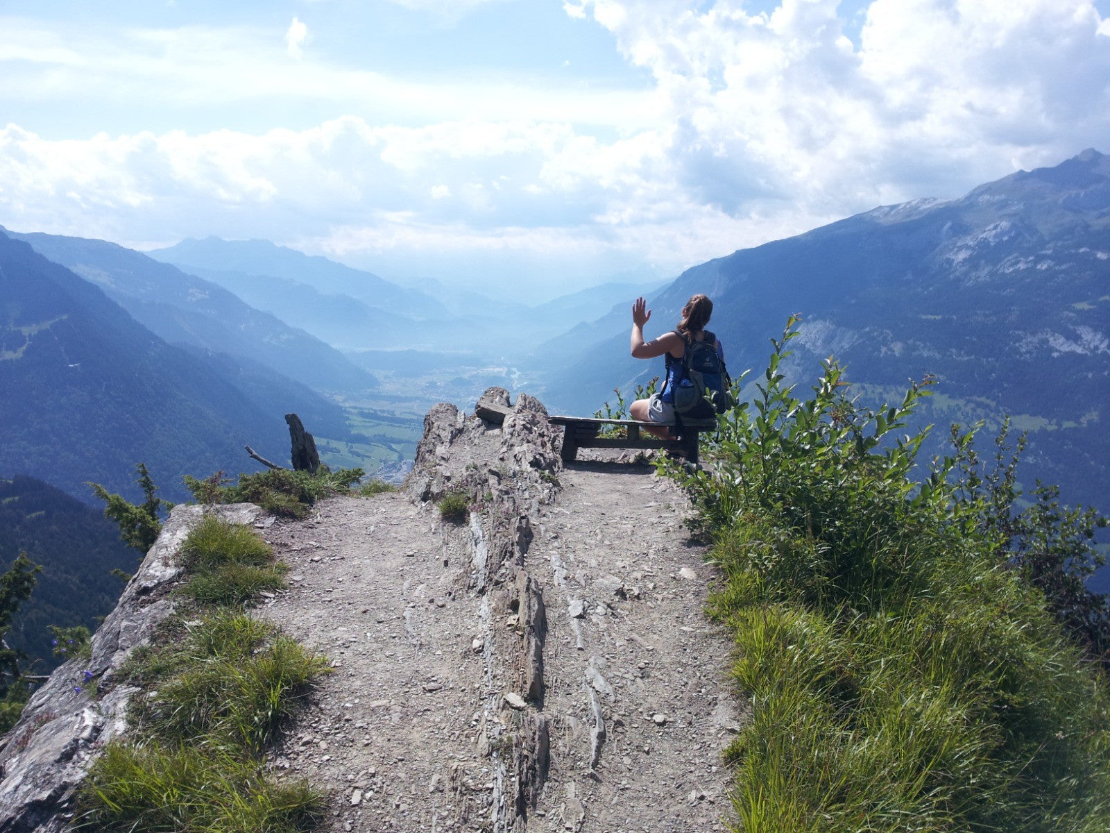 Hiker standing at a mountain viewpoint over a green valley