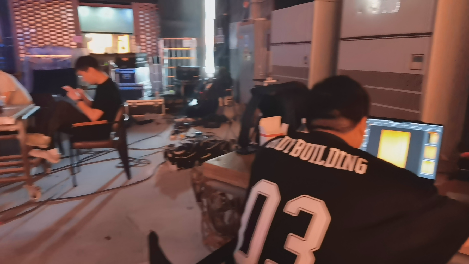 Crew member reviewing footage at a production monitor while the studio team works between takes.