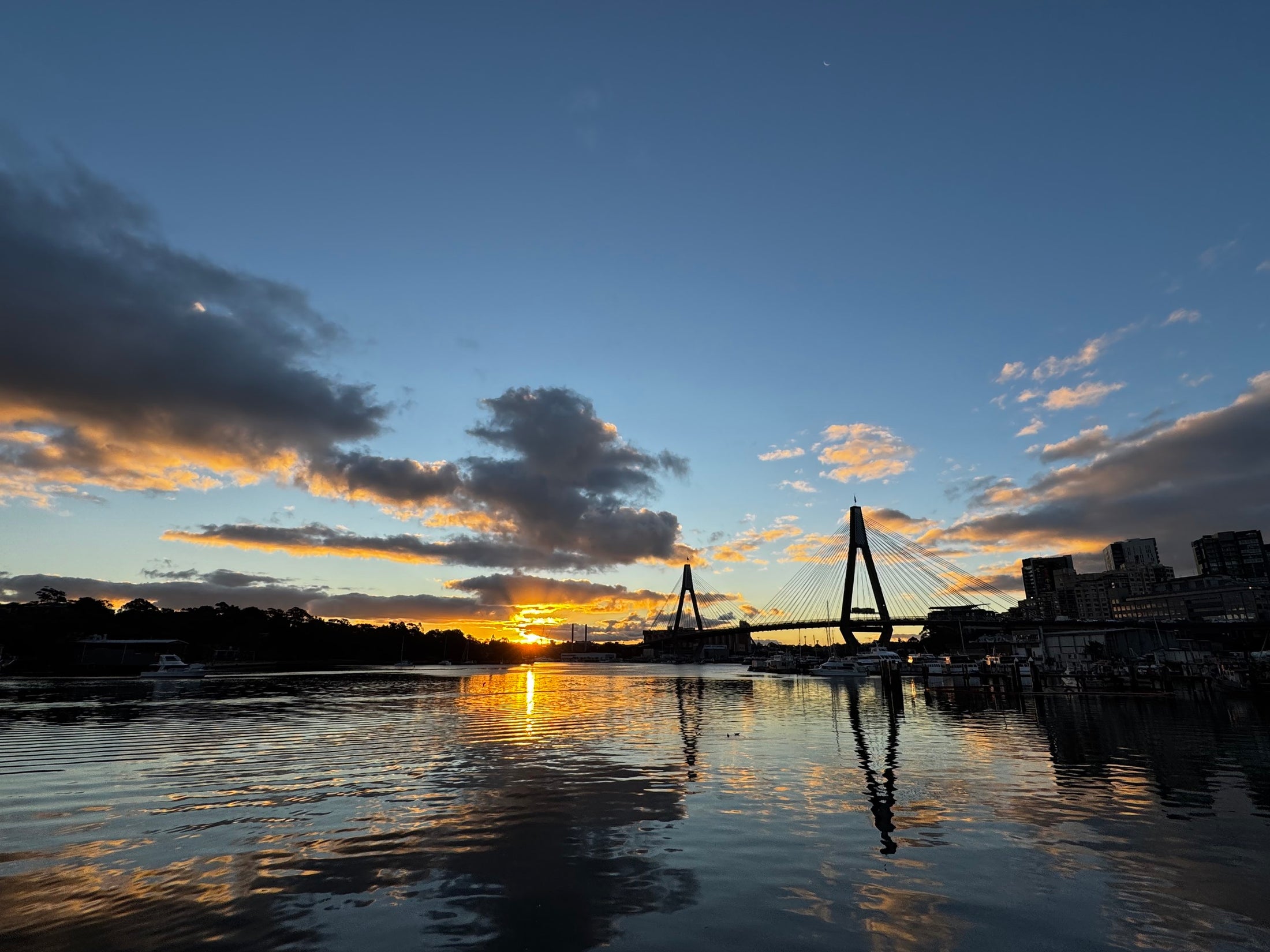 Sunset over a waterfront bridge and open skyline
